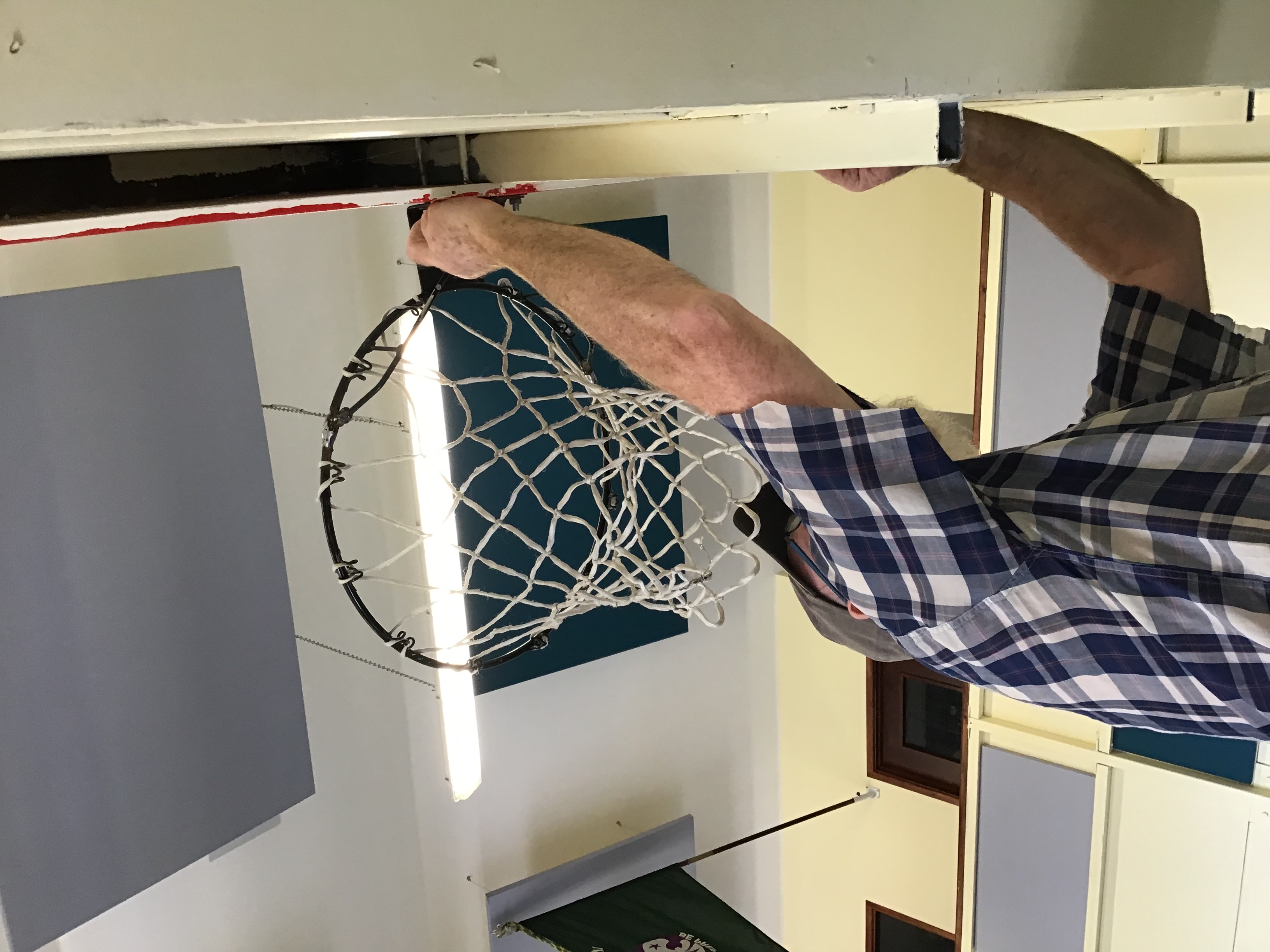 A Repair Cafe volunteer repairing the basket ball net at the Scout Hall