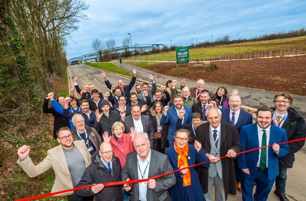 EDDC leader Cllr Paul Arnott cuts a ribbon to open Long Lane, together with representatives from Devon County Council, the South West Local Enterprise Partnership, East Devon District Council, Simon Jupp MP, Exeter College, Exeter Airport, contractors and local VIPs (photo credit: GRW Photography)