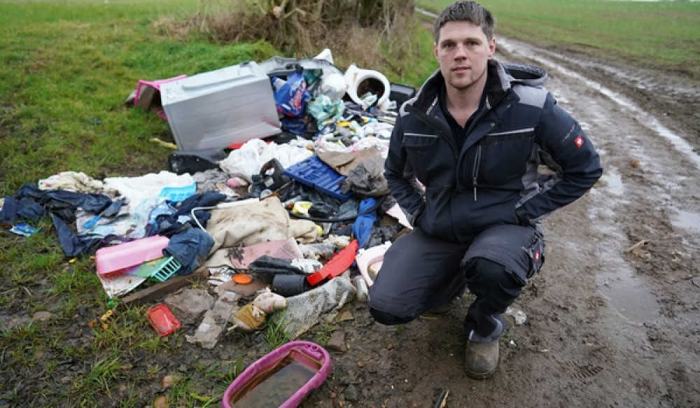 Will Oliver with the pile of rubbish at his farm. Photo: SWNS