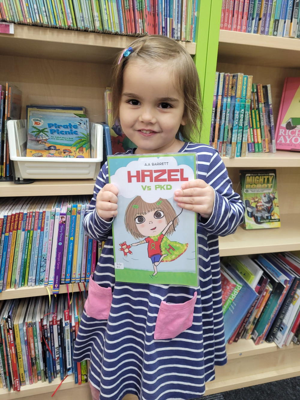  Four year old Hazel proudly holding a library copy of the book Hazel Vs PKD 
