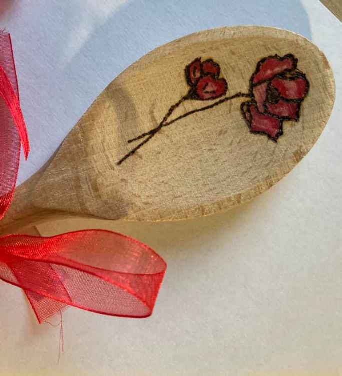 Elizabeth uses pyrography to etch precise poppy flowers onto the spoons