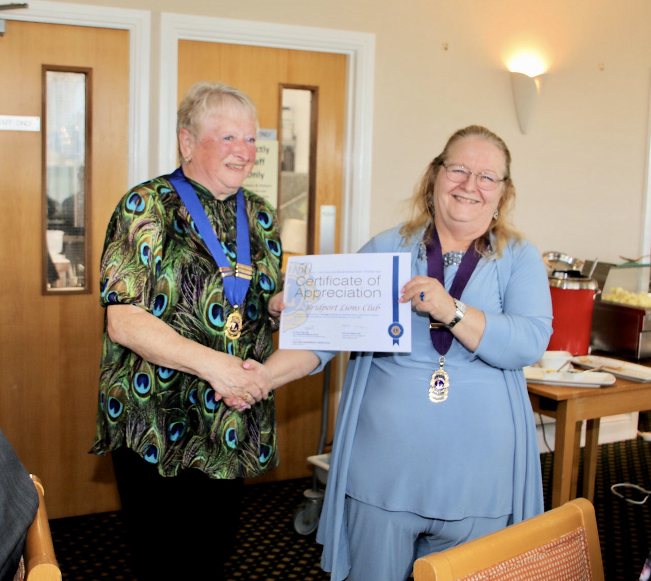 Bridport Lions Club president Sheila Greenaway receives the club's 50 year certificate from district governor Lesley Chudley 