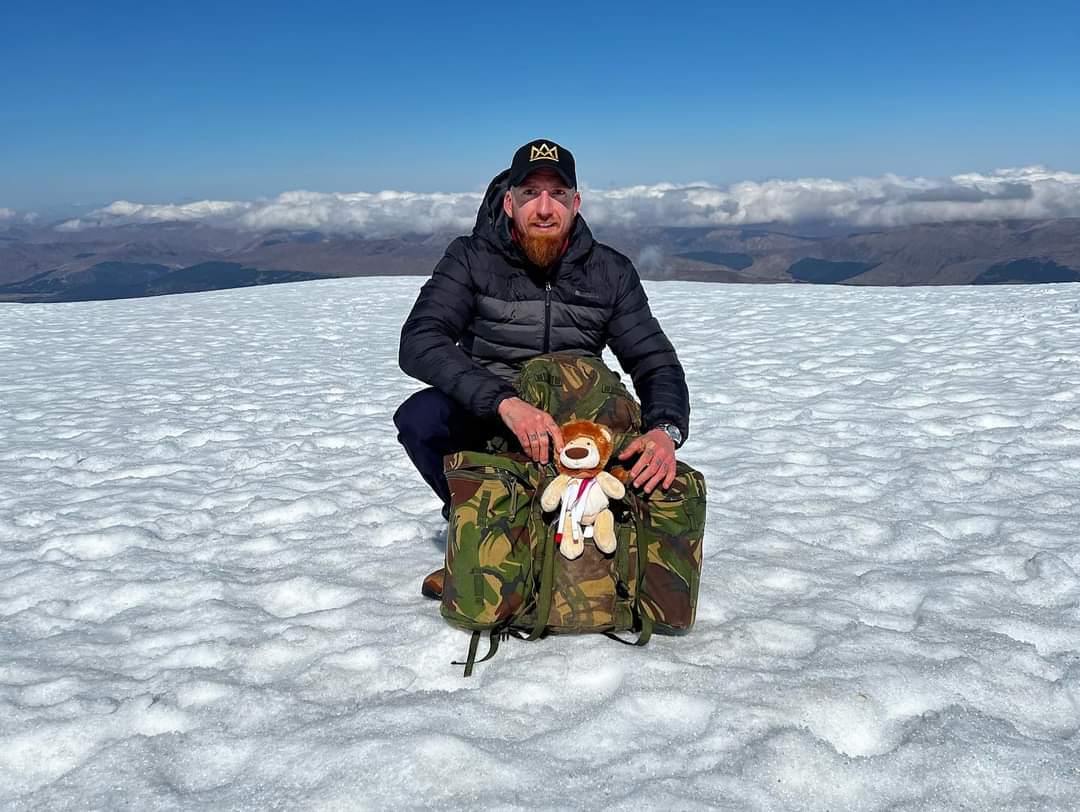 Alex Myers at the peak with Molly Ollys mascot Olly The Brave