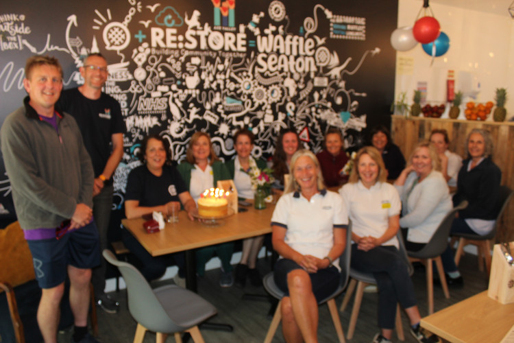 NHS staff and representatives from Waffle Seaton and Re:store celebrate the café's first anniversary