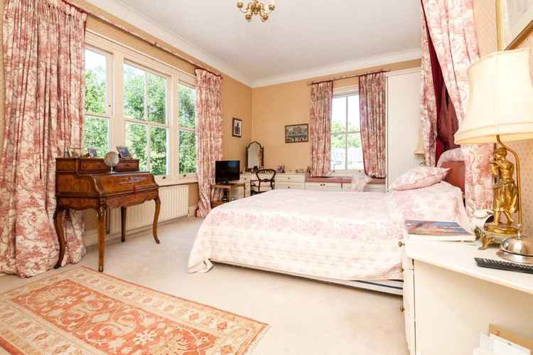 The apartment's main bedroom has wide windows and looks out onto a sea of green (Credit: Savills Wimbledon via Rightmove)