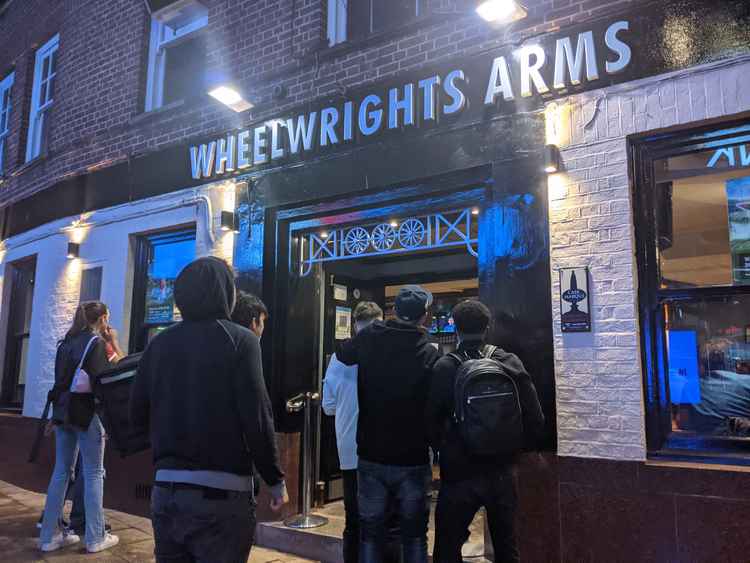 Fans outside the Wheelwright's Arms look in through the pub's windows, trying to catch a glimpse of the result (Credit: Nub News)