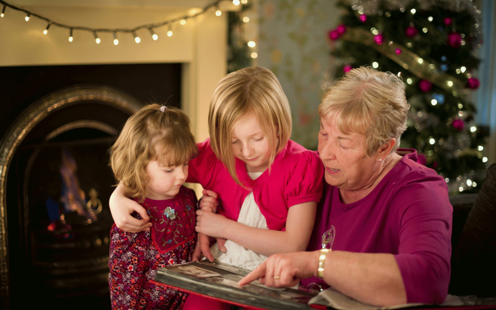 Grandma reading showing photo book to grandchildren (credit: Image supplied).