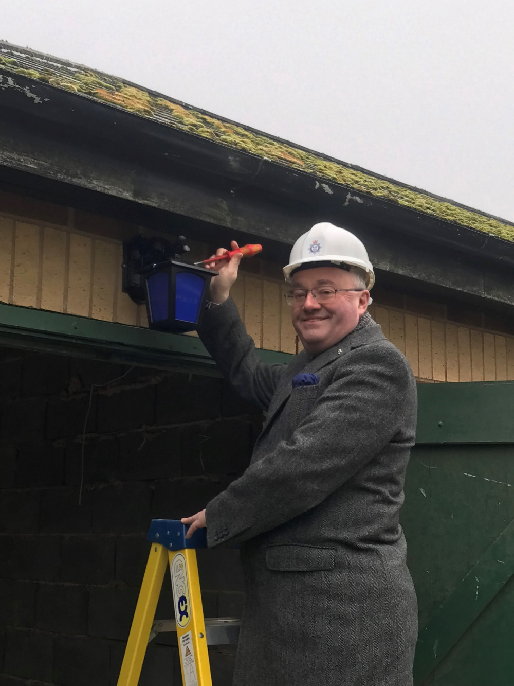 Rupert Matthews inspecting the fitting of one of the new blue lamps. Image credit: PCC Rupert Matthews.
