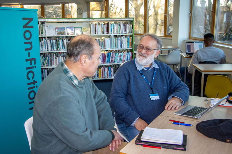Volunteer digital champion, Mike Watson, providing advice in Dorchester Library