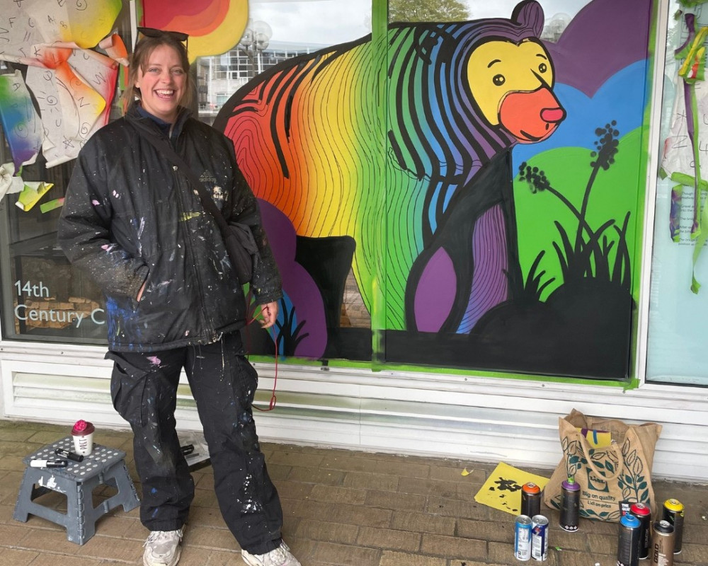 Local artist Jeru Nomi stands next to her mural of Spectrum the bear (Photo: Kingston First)