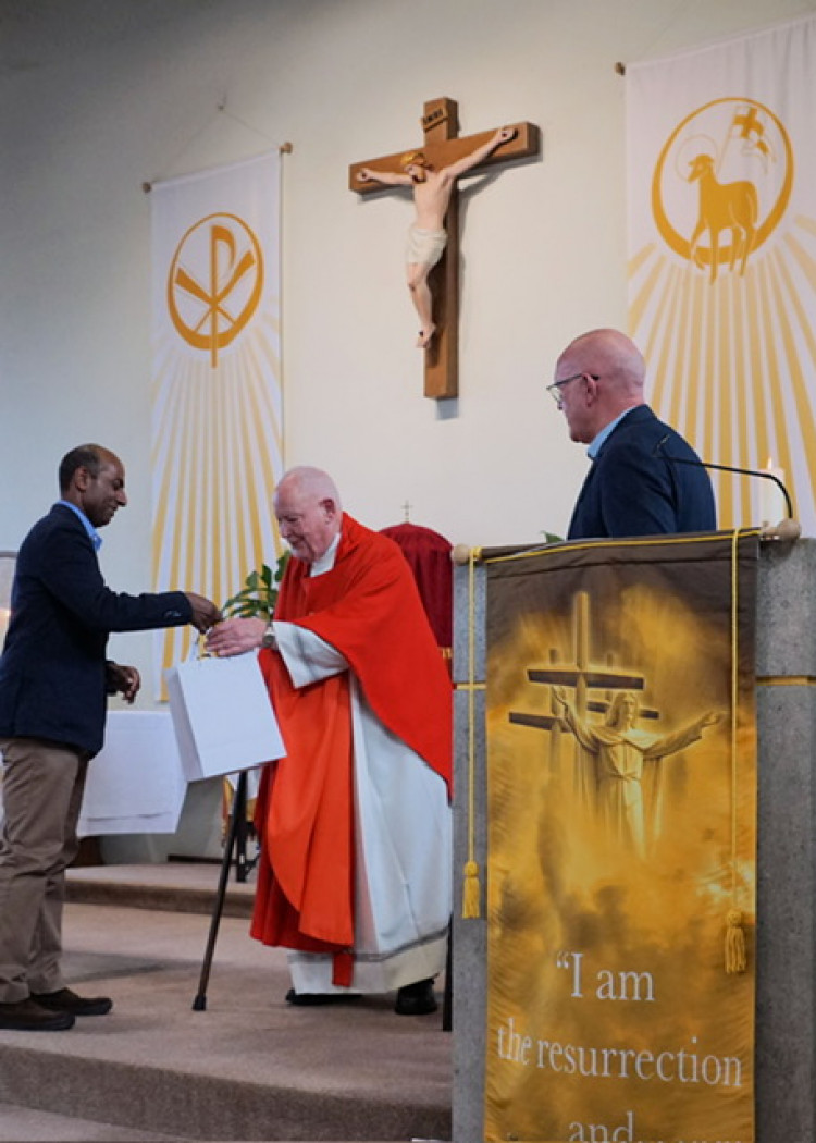 Father Brian being presented with gifts & a card signed by parishioners by Roger Chinnon (left) & Mike Walsh (right).