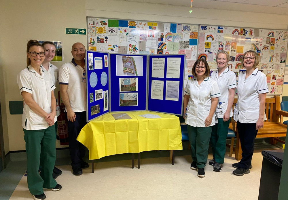 Members of the acute therapy team pose with plans for the new therapy garden at Stepping Hill Hospital (Image - Stockport NHSFT)