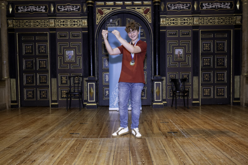 Charlie with his award on stage at the Sam Wanamaker Playhouse. Image credit: Oakham School. 