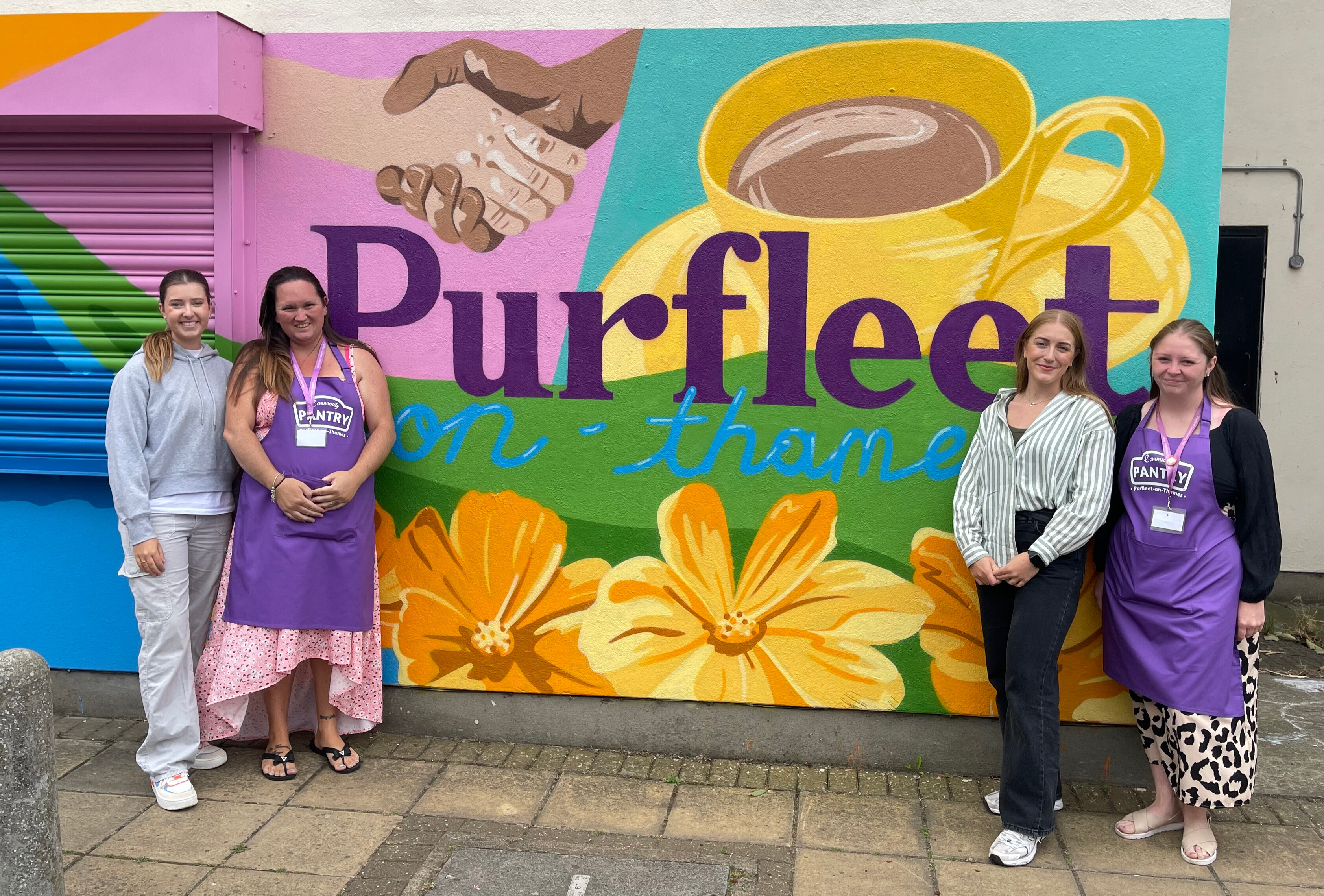 Brittany and Kirsty from K&B Design Ltd in front of their mural with Community Pantry volunteers.