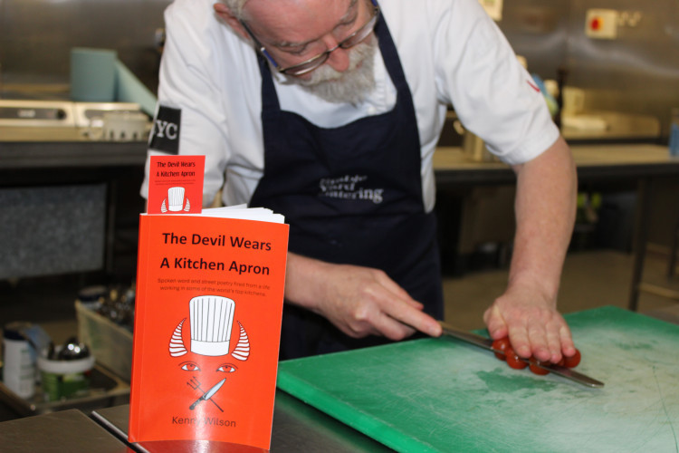 Kenny Wilson, slicing tomatoes next to his new book. (Image - Macclesfield Nub News)