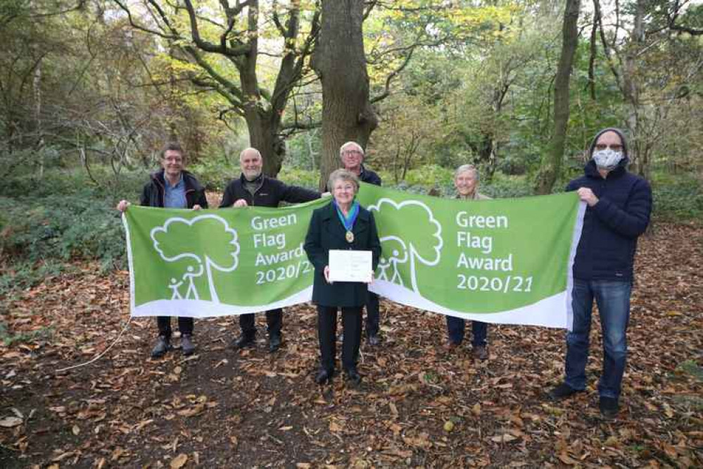 Volunteers and staff stood with Green Flags in Crackley Woods