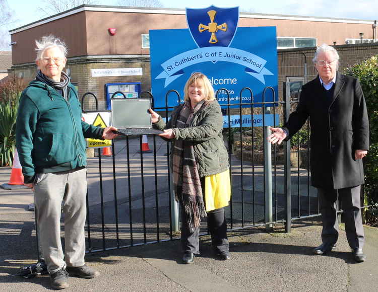 Wells Lions secretary Ian Williams presents the first laptop to St Cuthbert's Junior School head Helen Mullinger watched by Wells Coronavirus spokesperson Philip Welch