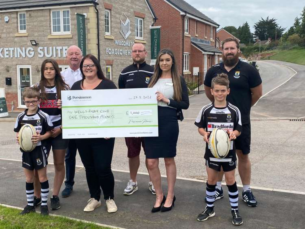 Persimmon sales advisor Thea presents the money to representatives of Wells Rugby Club