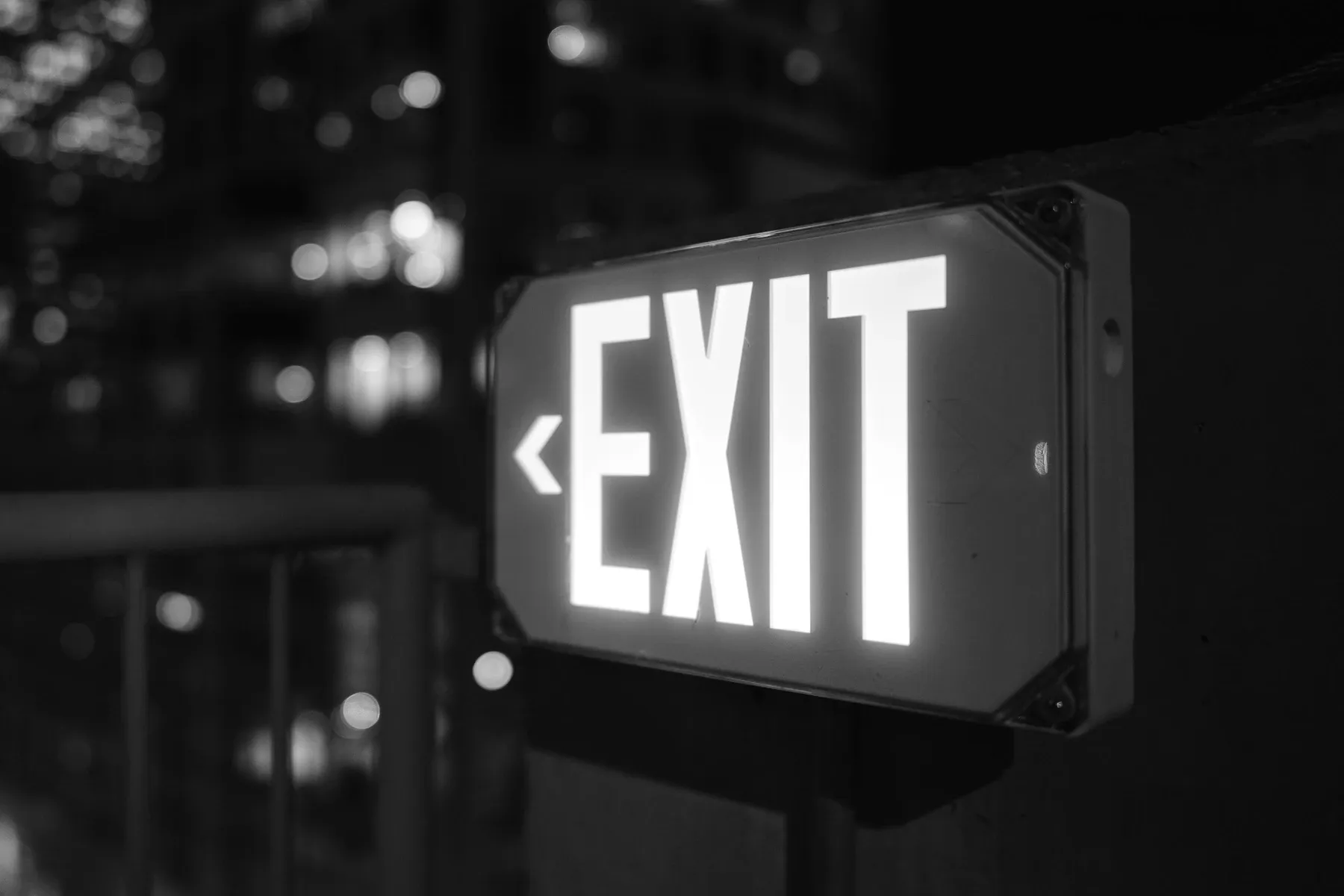 An illuminated exit sign above a doorway in a darkened room.
