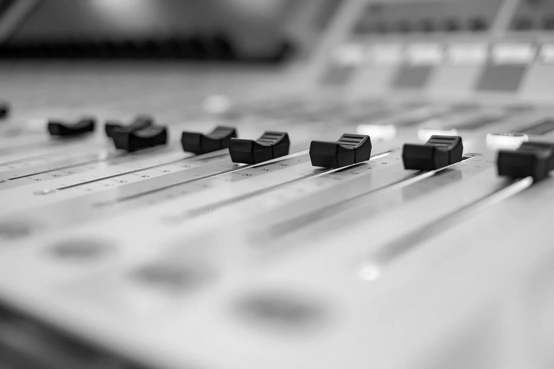 A row of mixing-console faders, each set at a different position along its track.