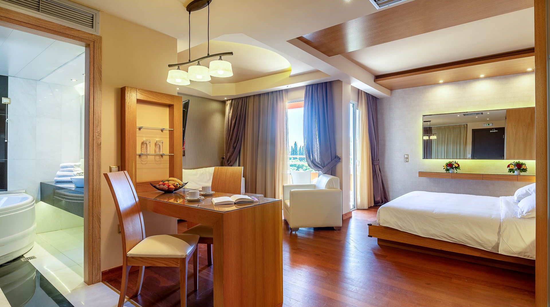 The interior of the room with the desk, the balcony, the bed and a glimpse of the jacuzzi