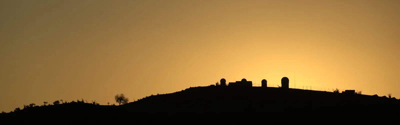 The domes of El Sauce in silhouette on the ridge against an orange dusk