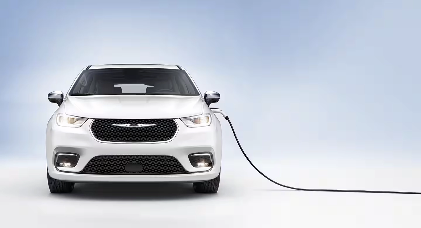 A white Chrysler Pacifica Hybrid plugged into a wall