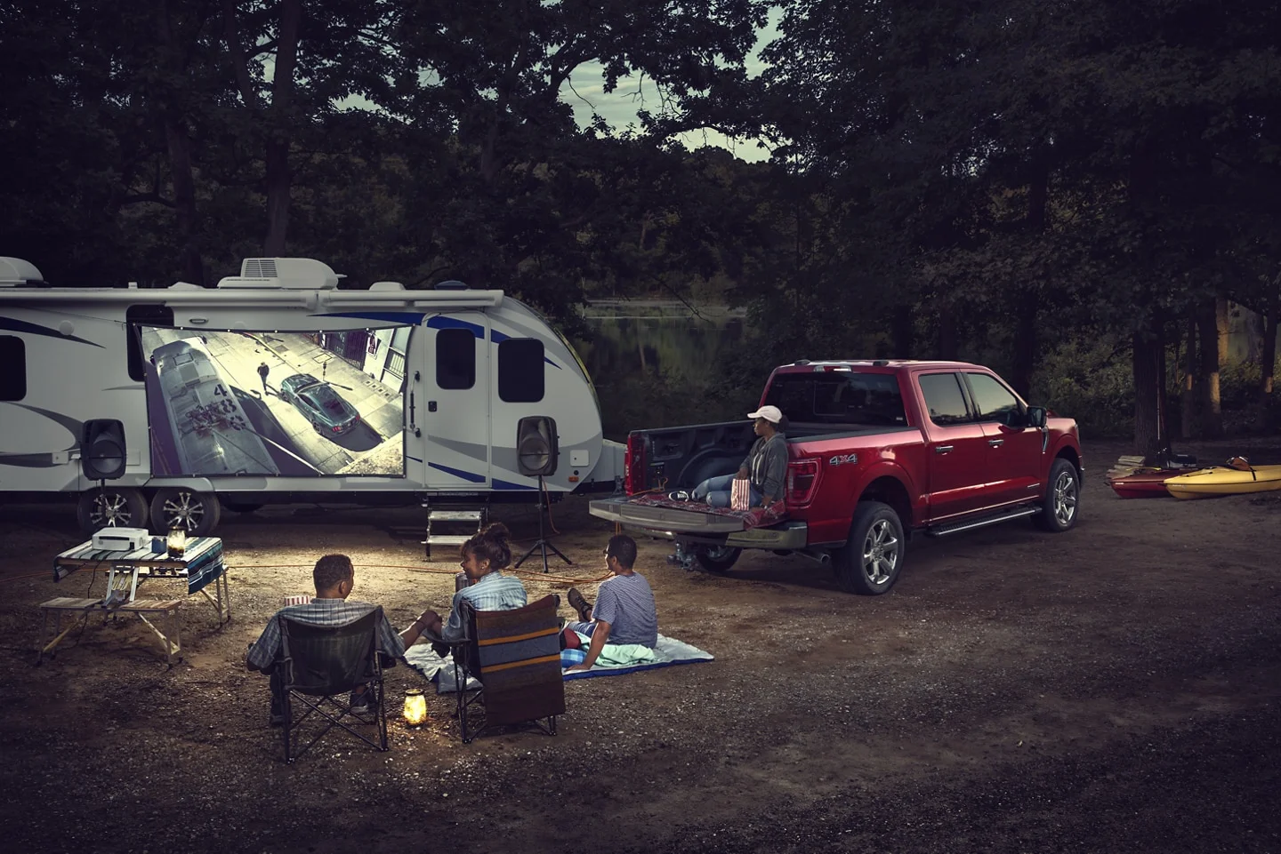 Family camping watching a movie outside with a red F-150