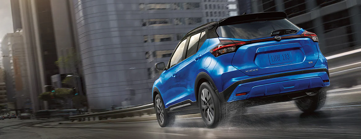 2024 Nissan Kicks shown in blue rear view with city on the background.