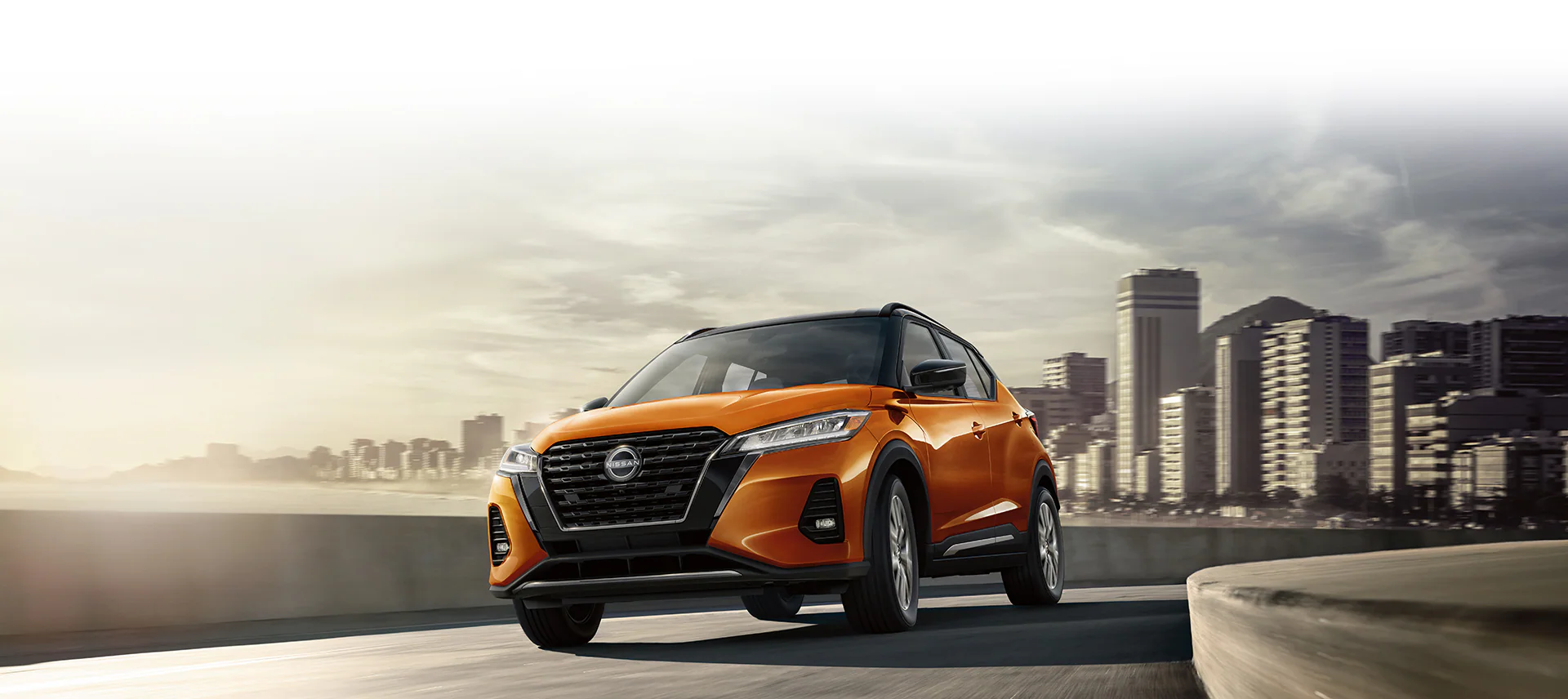 2024 Nissan Kicks on a highway with city in background showing bold front design