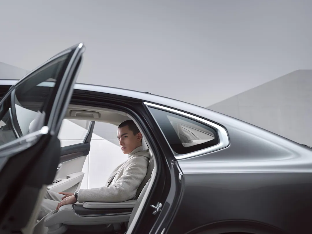 A man sitting in the back seat of a Volvo S90.