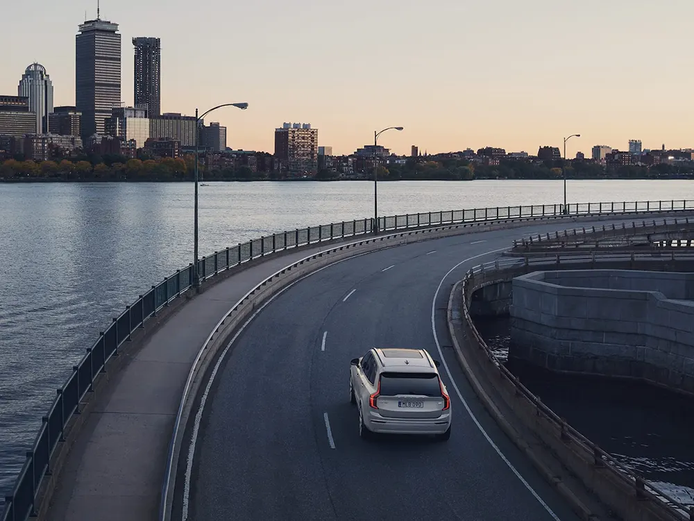 A Volvo XC90 Recharge follows a curve along the side of a river.