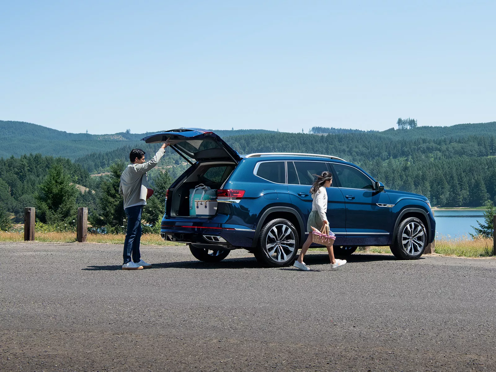 2023 VW Atlas Design Overview An Atlas shown in Blue Metallic, drive opening trunk near a lake.