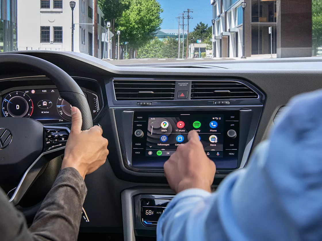 Passenger selecting app from dash infotainment touchscreen display with left index finger. 