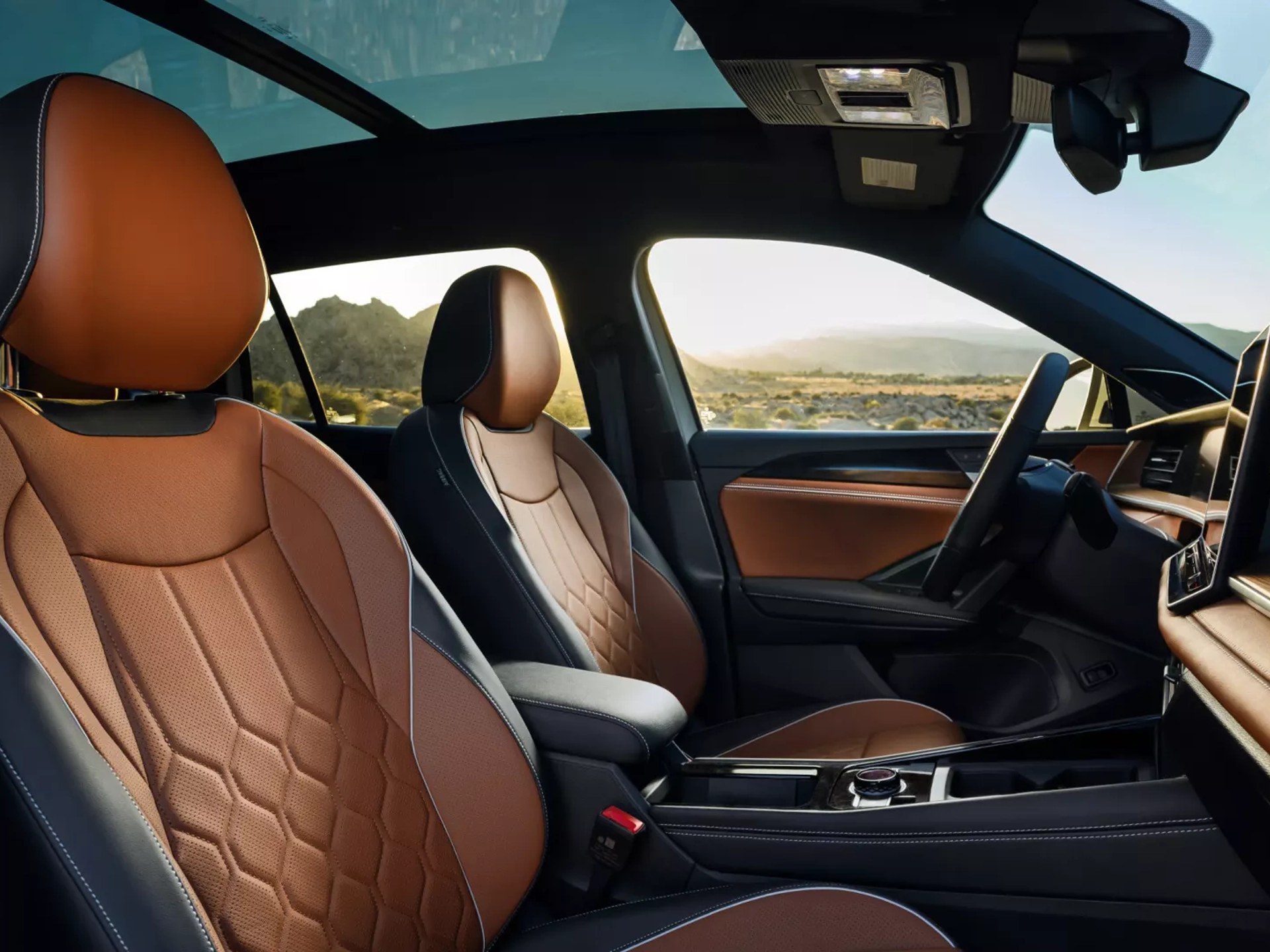 Interior view of a Tiguan shown in available Amber Brown leather looking from passenger's side across the dash and out the driver's side windows with mountains and a valley visible in the background..