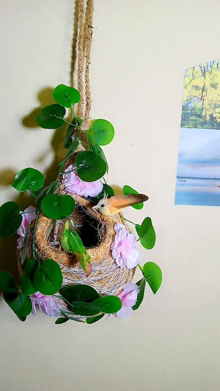 A beautiful bird nest where included two birds, some flower and some artificial green leaf. 1