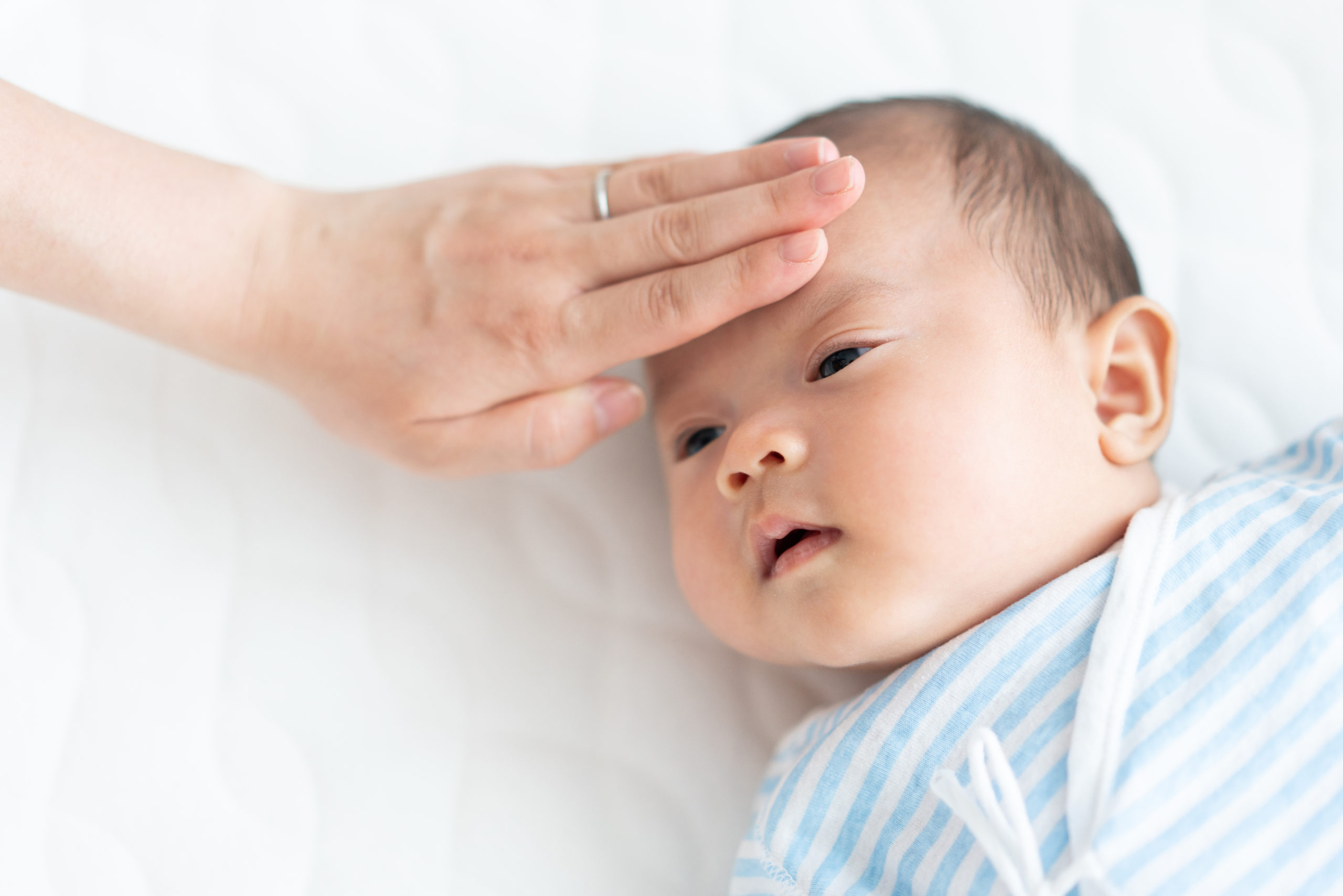 赤ちゃんの額に手を当てて熱を計る女性