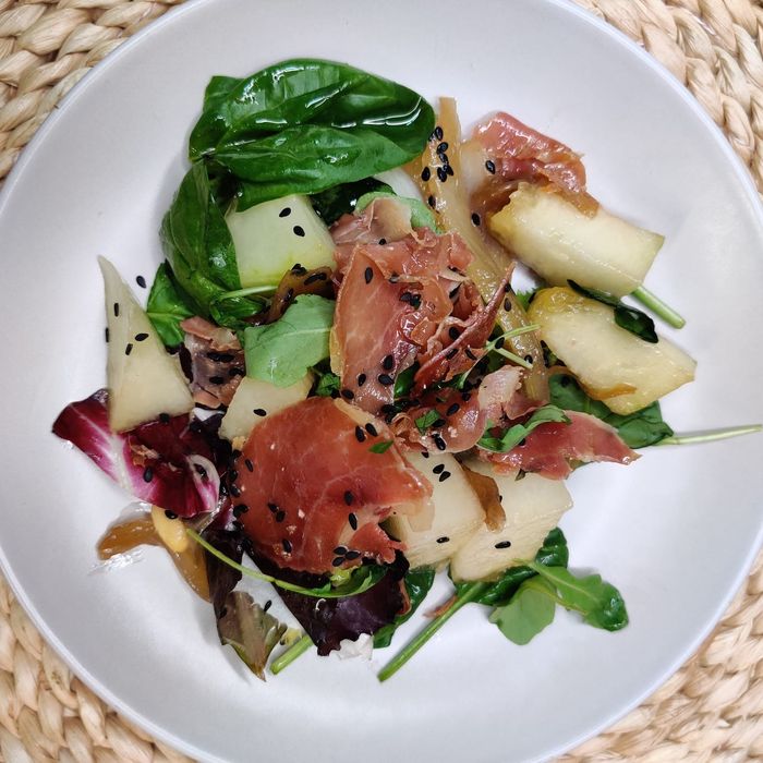 Grüner Salat mit Melone, karamellisierten Zwiebeln und Schinkenstreifen