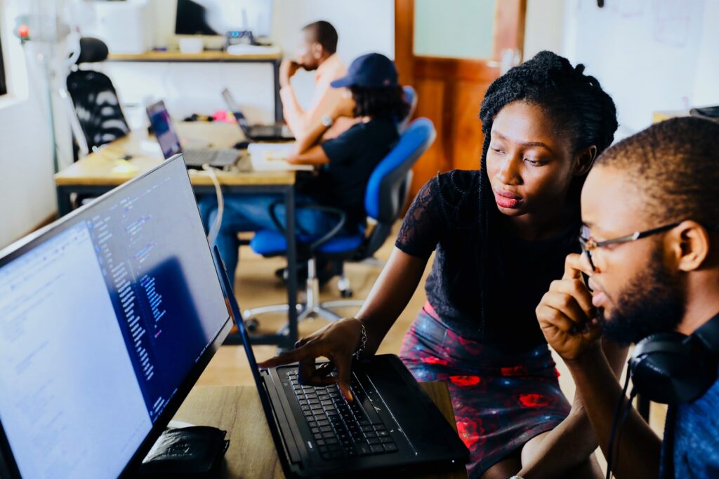 Duas pessoas olhando a tela do computador e conversando sobre ética profissional