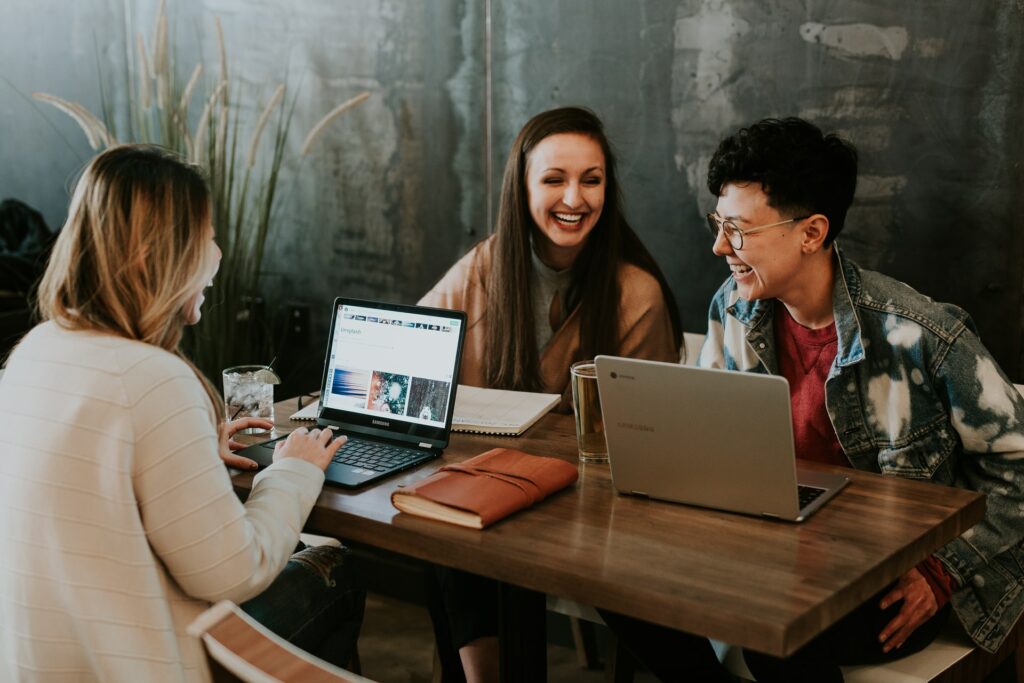 Uma bancada com 3 pessoas com notebooks, conversando e falando sobre gestão de pessoas