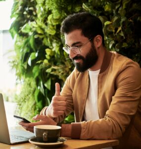 Homem sentado com um notebook e um café ao lado, ao longo do processo de avaliação de desempenho à distância