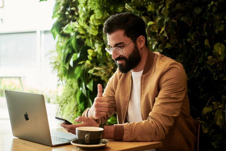 Homem sentado com um notebook e um café ao lado, ao longo do processo de avaliação de desempenho à distância