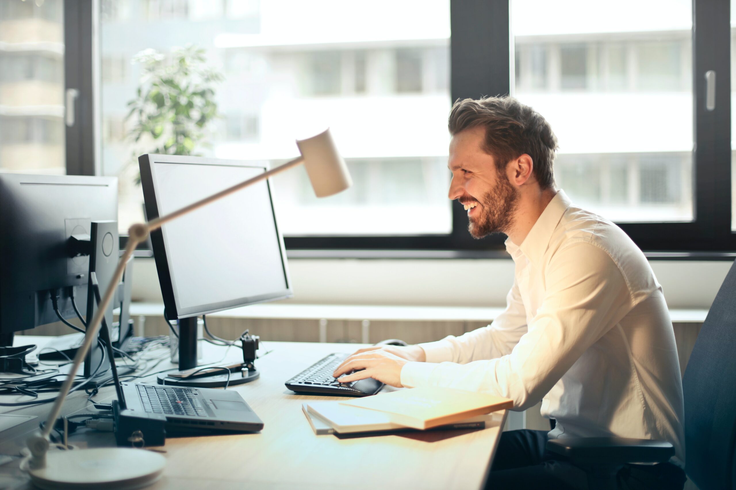 Homem sorrindo em frente ao seu desktop, sob mesa de maneira em um escritório,