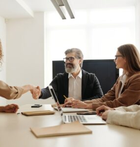 Quatro pessoas sentadas ao redor de uma mesa em um ambiente de entrevista de emprego, sendo dois homens e duas mulheres.