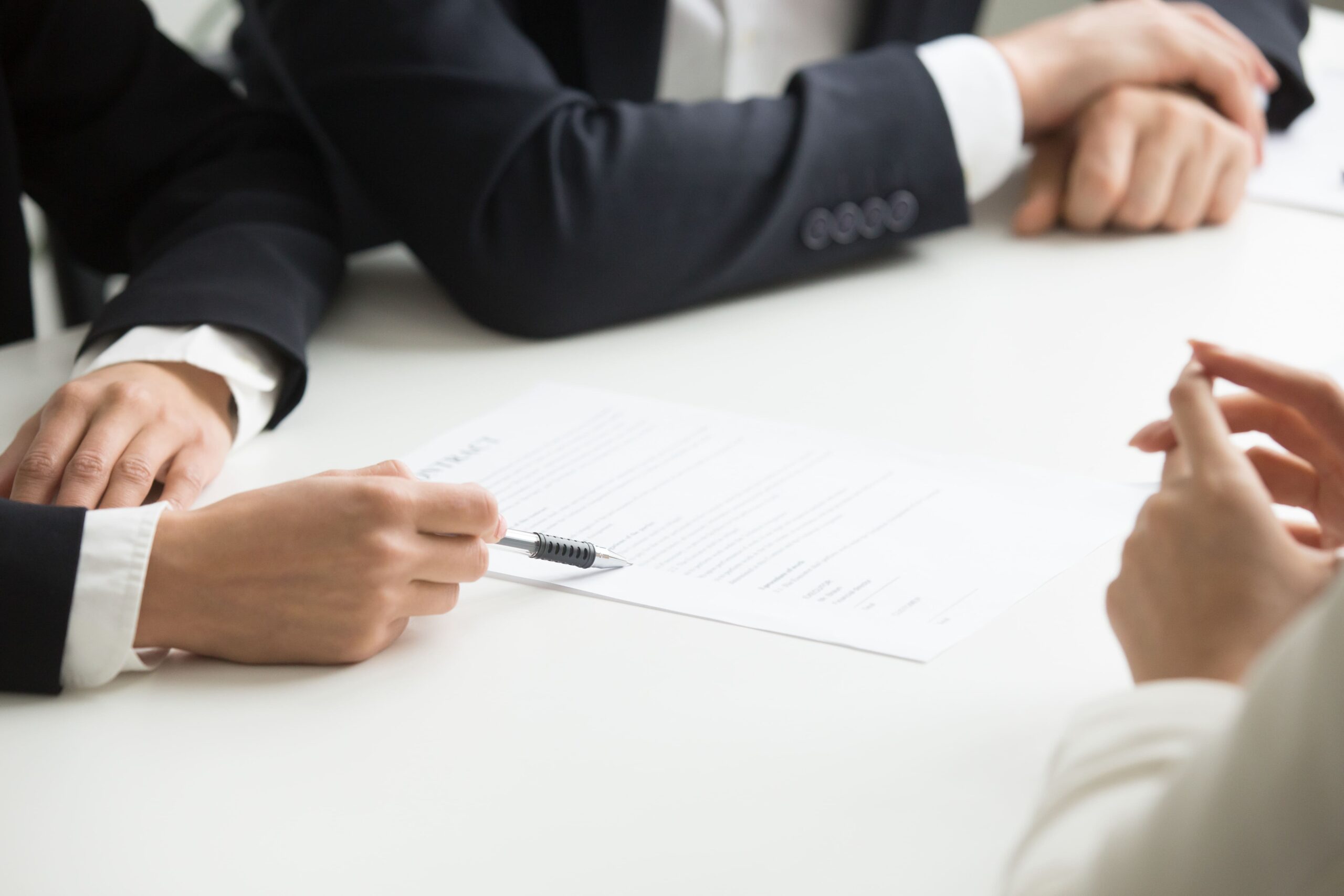 Pessoas de terno sentadas em uma mesa elaborando o texto que está sendo escrito em um papel, representando a formulação das mudanças na regras de teletrabalho.