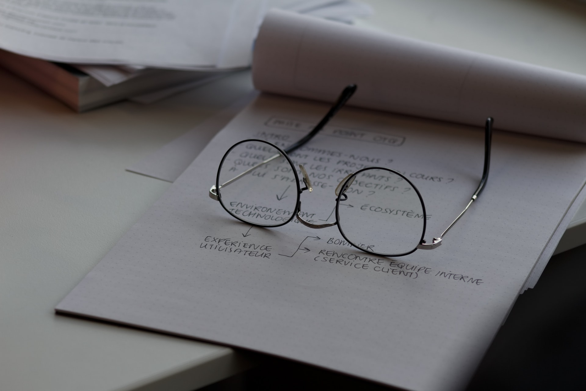 Imagem com um bloco de notas e um óculos redondo falando sobre desenvolver competências em gerenciamento de projetos