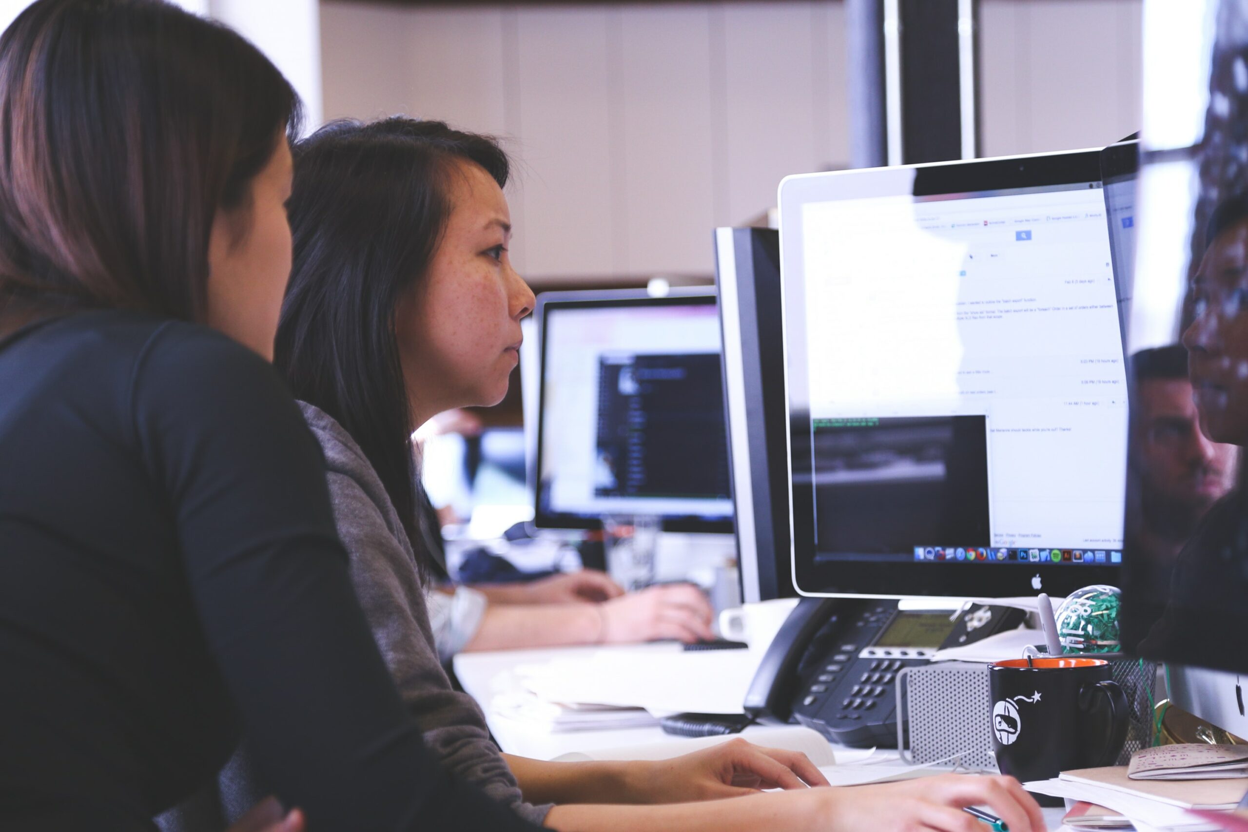 duas mulheres olhando computadores