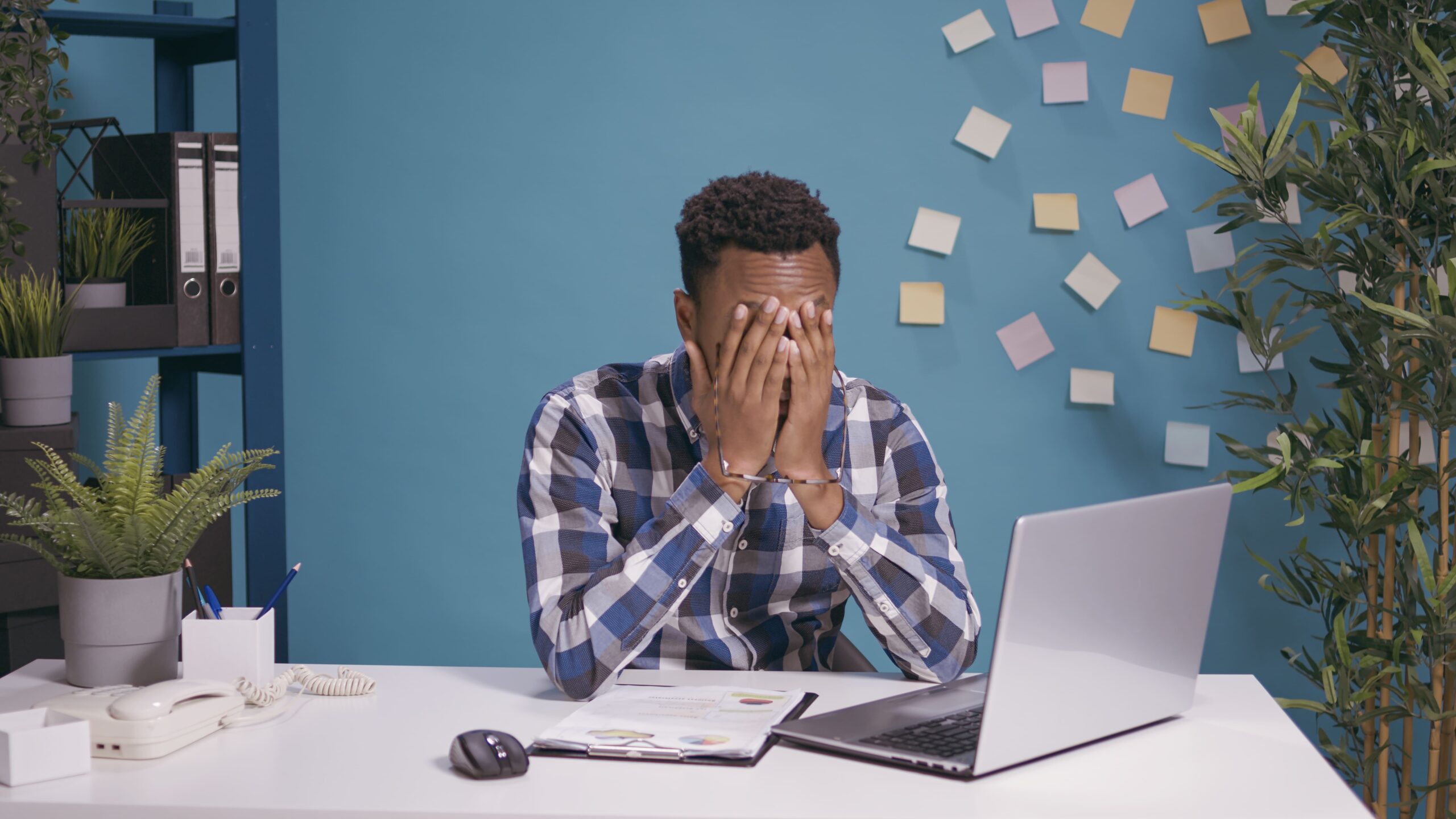 Homem levando à mão ao rosto em ambiente de trabalho, demonstrando descontentamento ou irritação, o que representa uma cultura organizacional tóxica