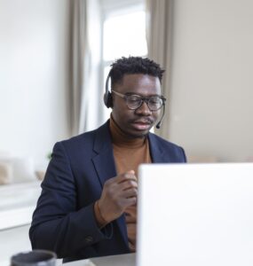 Homem olhando para a tela do notebook e utilizando um fone de ouvido.