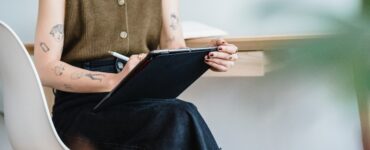 mulher sentadas com uma caneta anotando em tablet